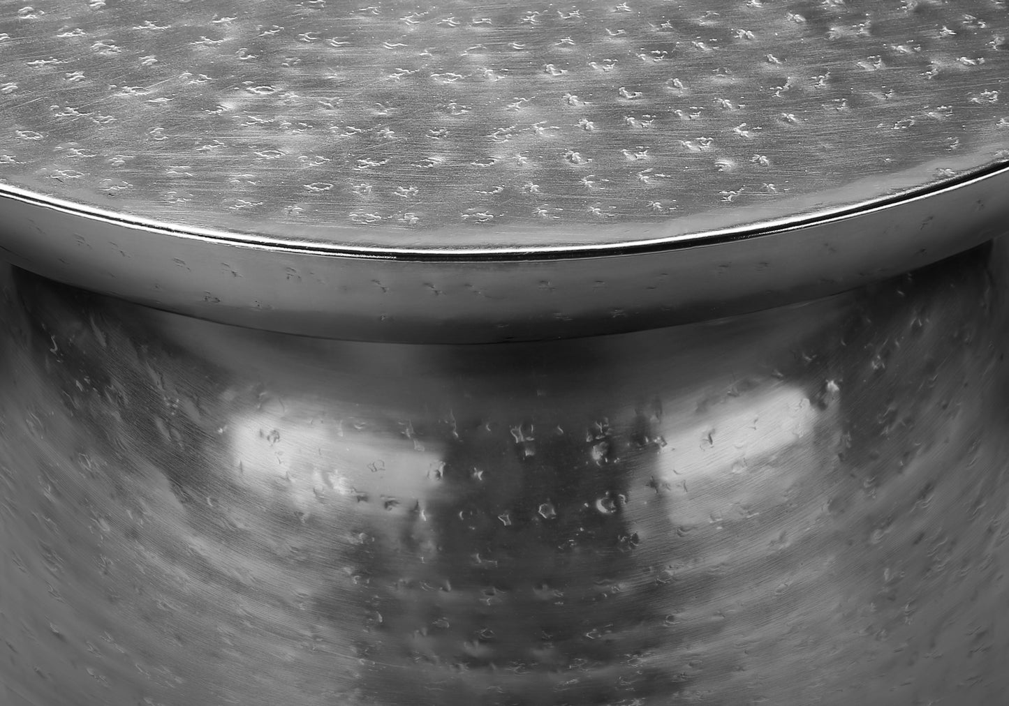 Textured metallic side table with hammered silver finish and rounded edge