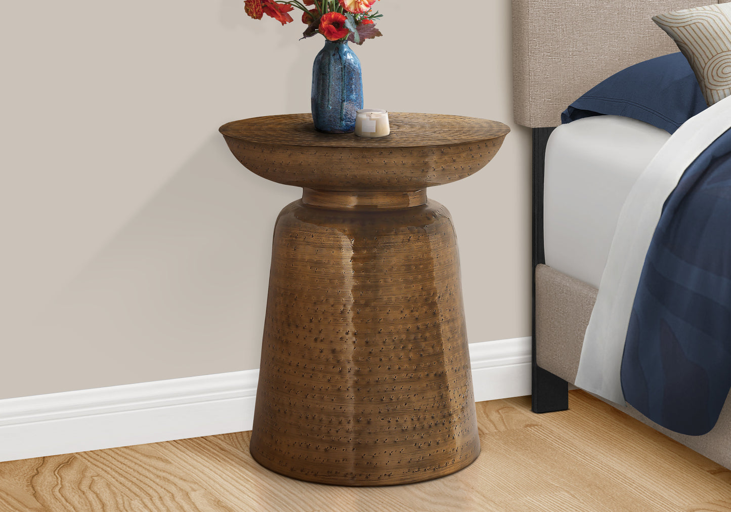 Hammered bronze accent table with a floral vase and candle