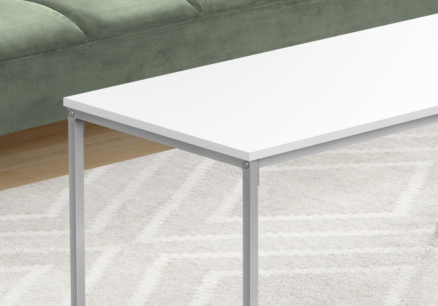 Modern white coffee table with minimalist grey metal legs and a tufted sage green sofa