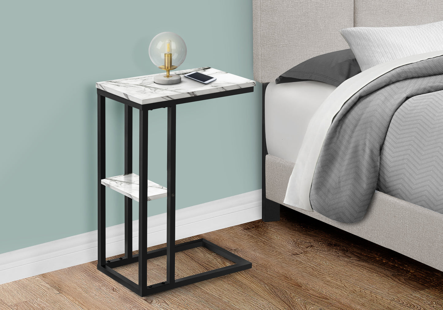 Marble top ctable with black metal frame and shelf next to a bed