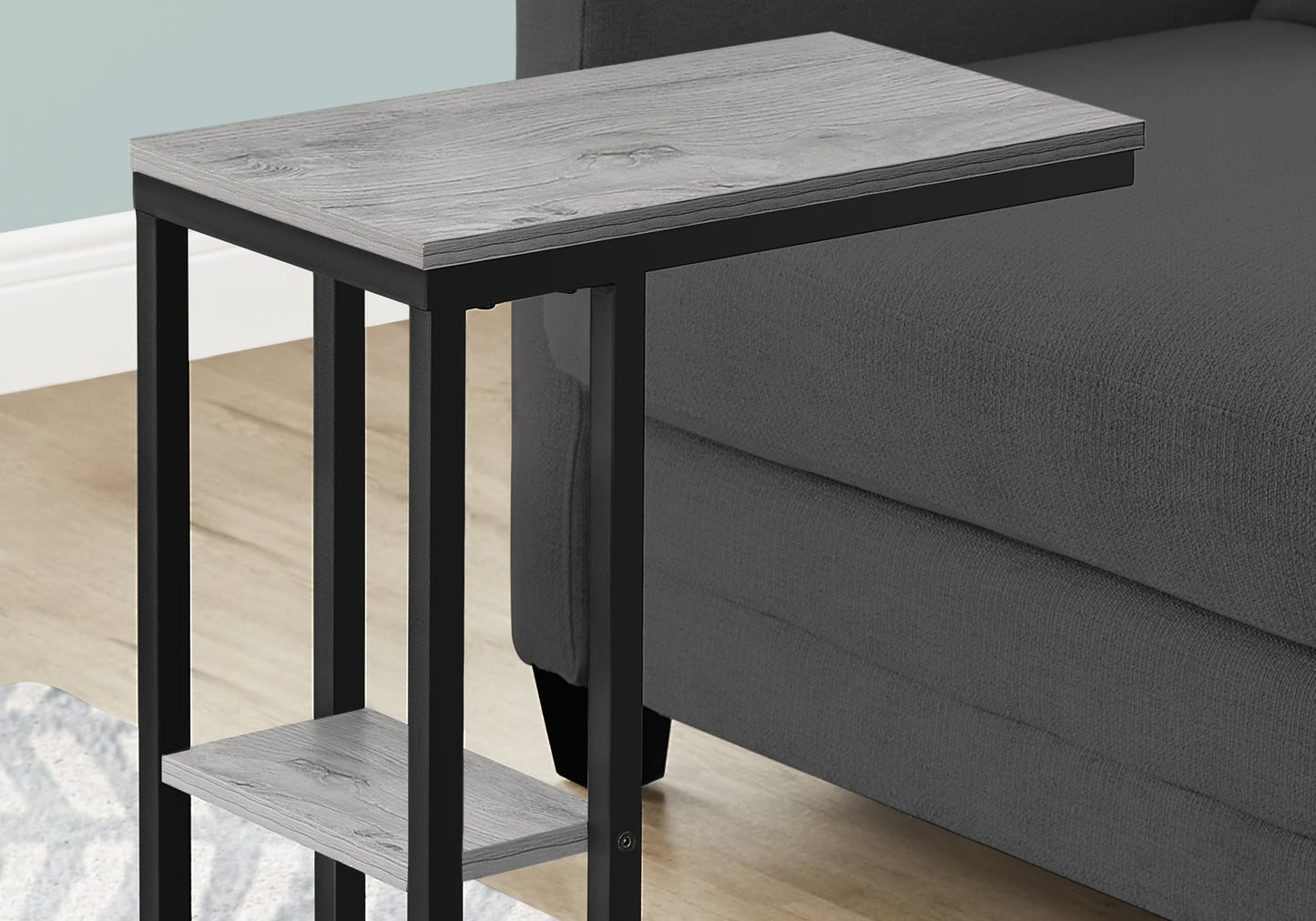 Gray wood grain C table with black metal frame slides under sofa for easy access