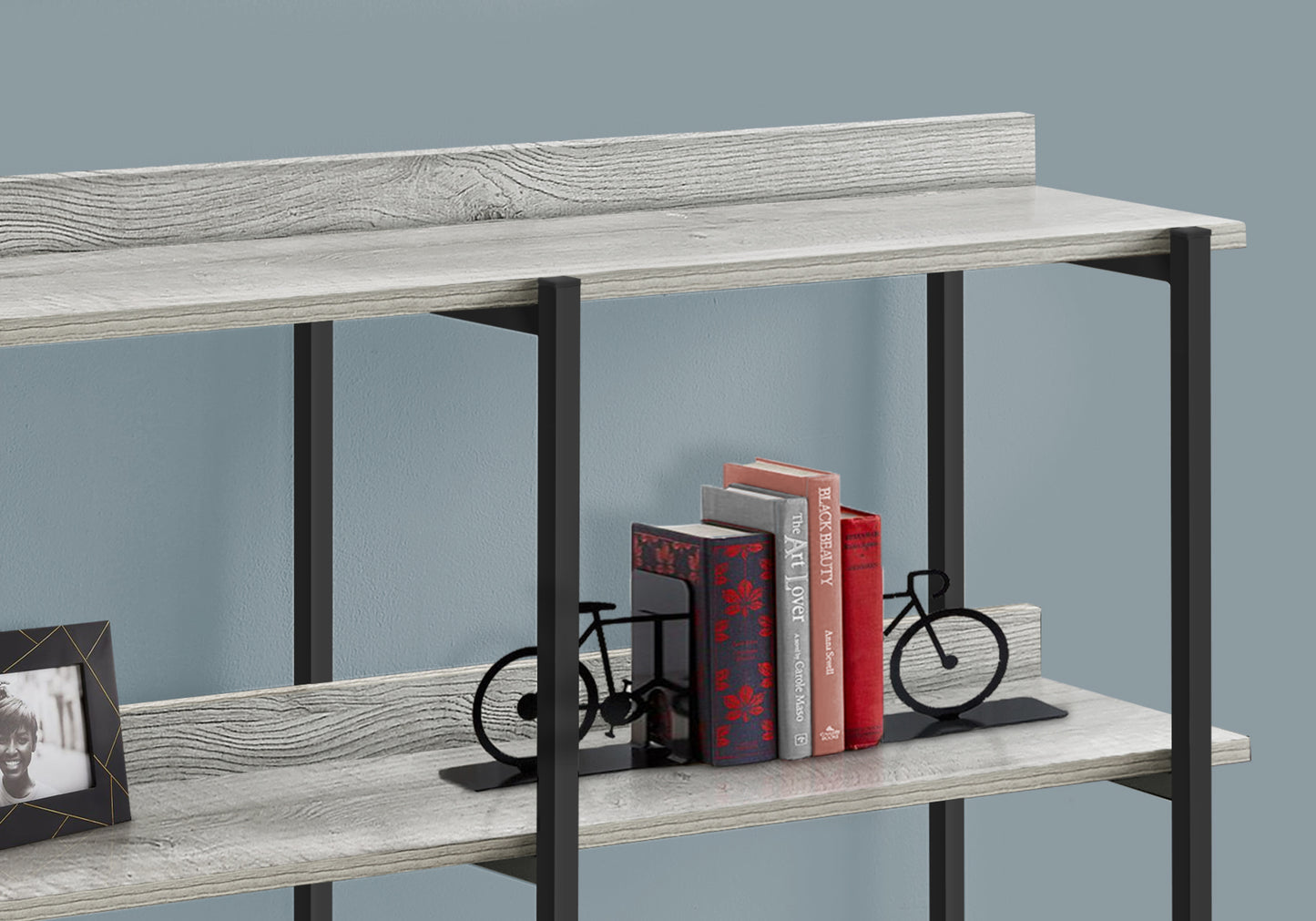 Set of two black metal bicycle bookends supporting a stack of decorative books on a shelf