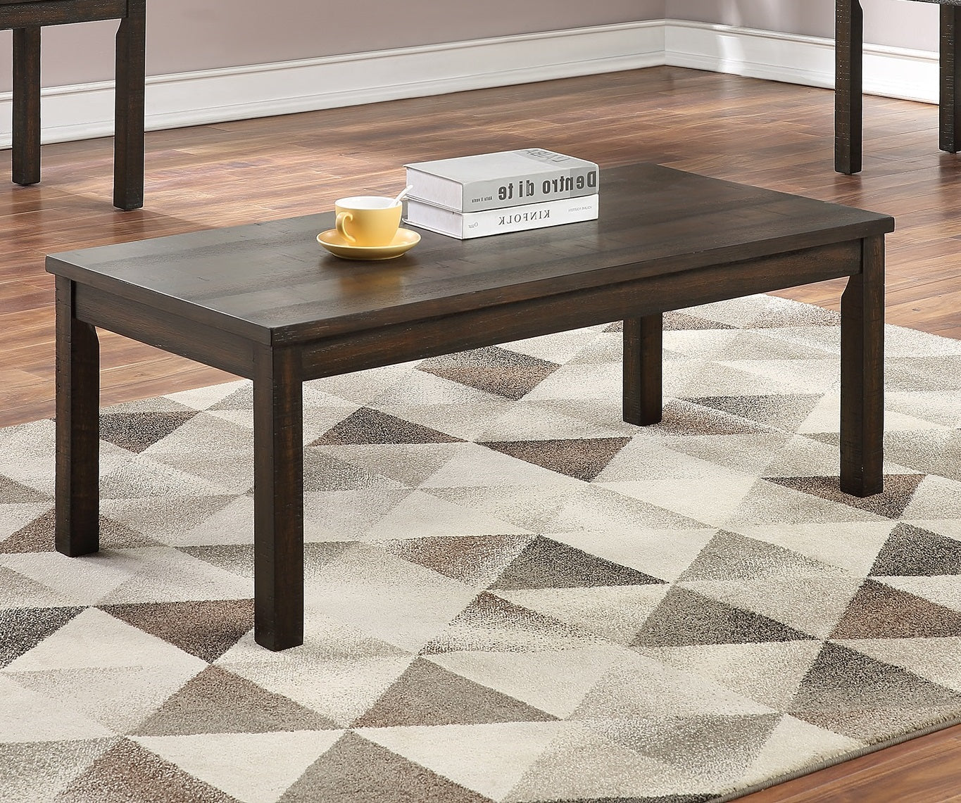 Dark wood rectangular coffee table with a geometric rug and a yellow teacup