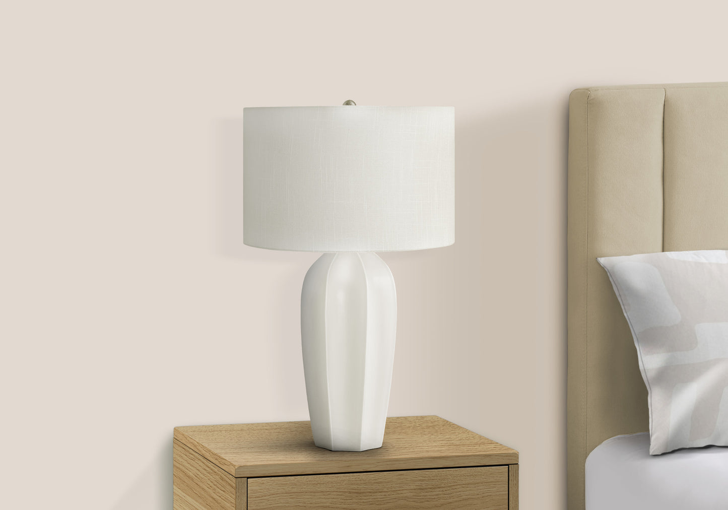 White ceramic table lamp with textured shade on a wooden nightstand