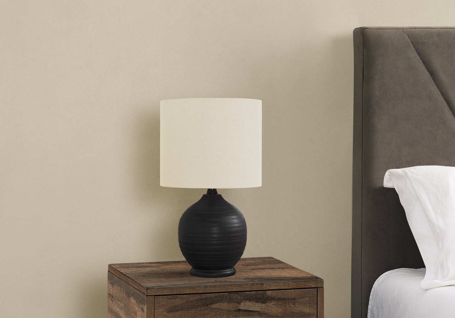 Black ceramic ribbed table lamp with cream linen shade on wooden nightstand