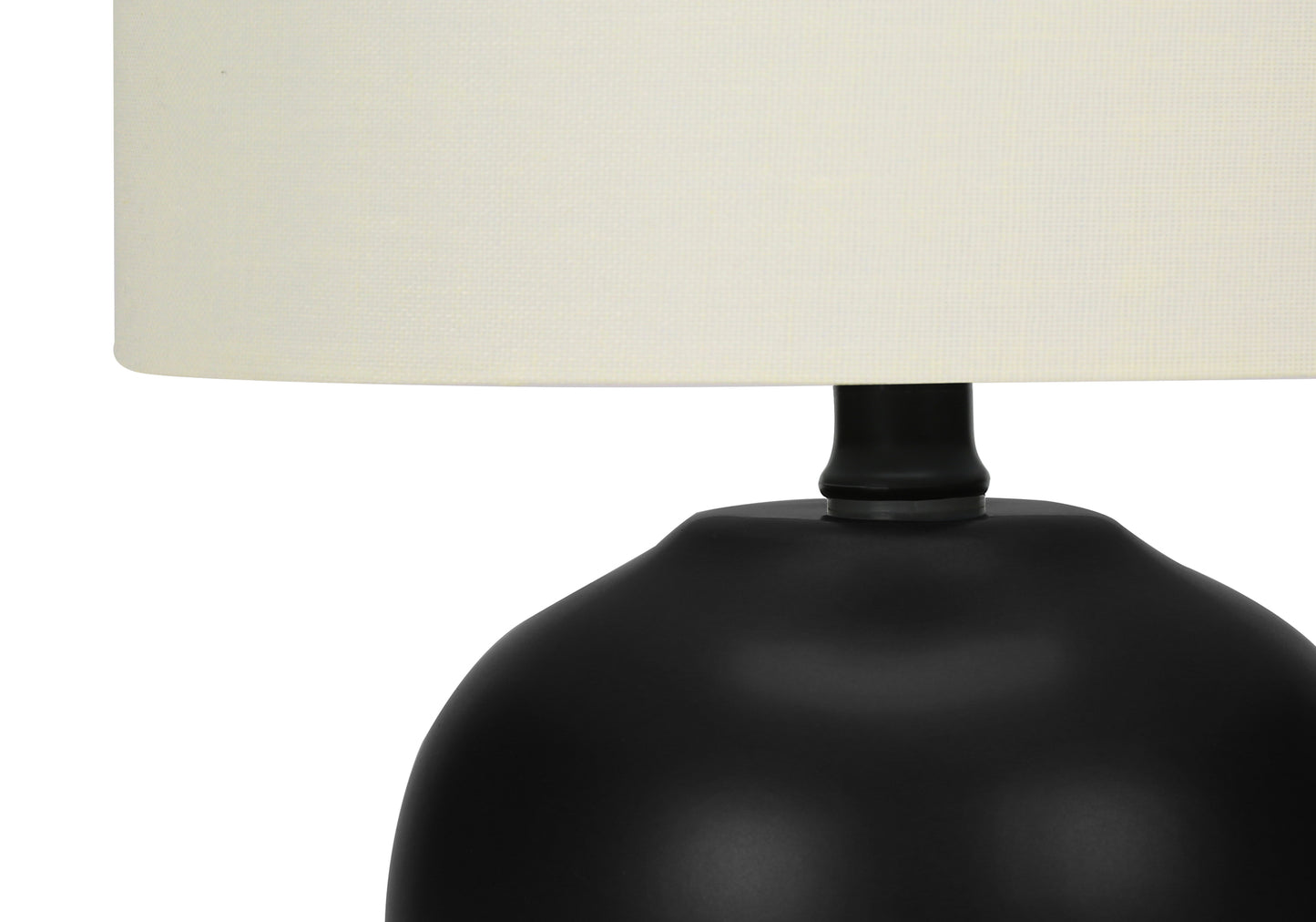 Closeup of a black ceramic base table lamp with a cream fabric shade