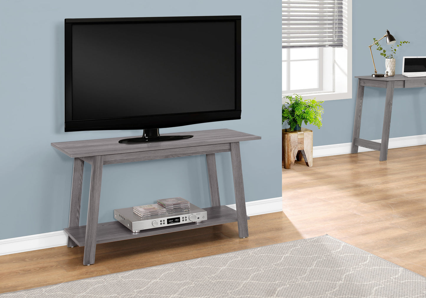 Gray wood grain console table with a media shelf holding CDs and a receiver
