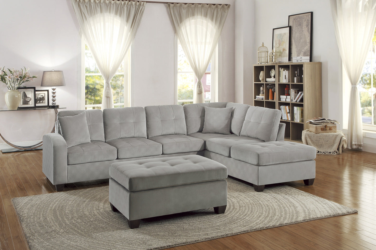 Gray velvet sectional sofa with tufted cushions and matching ottoman in a living room
