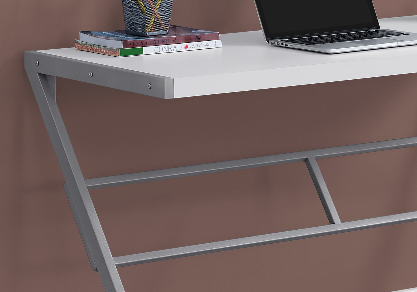 Modern white desk with metal frame laptop and books on top