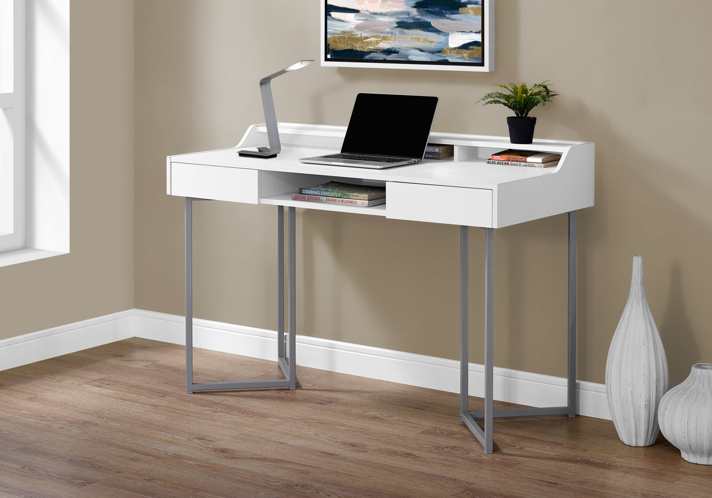 Modern white writing desk with silver legs featuring a laptop and decorative items