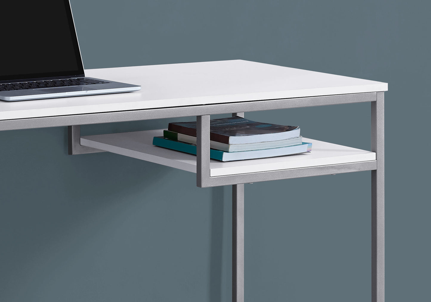 White minimalist desk with sleek silver frame and stacked books