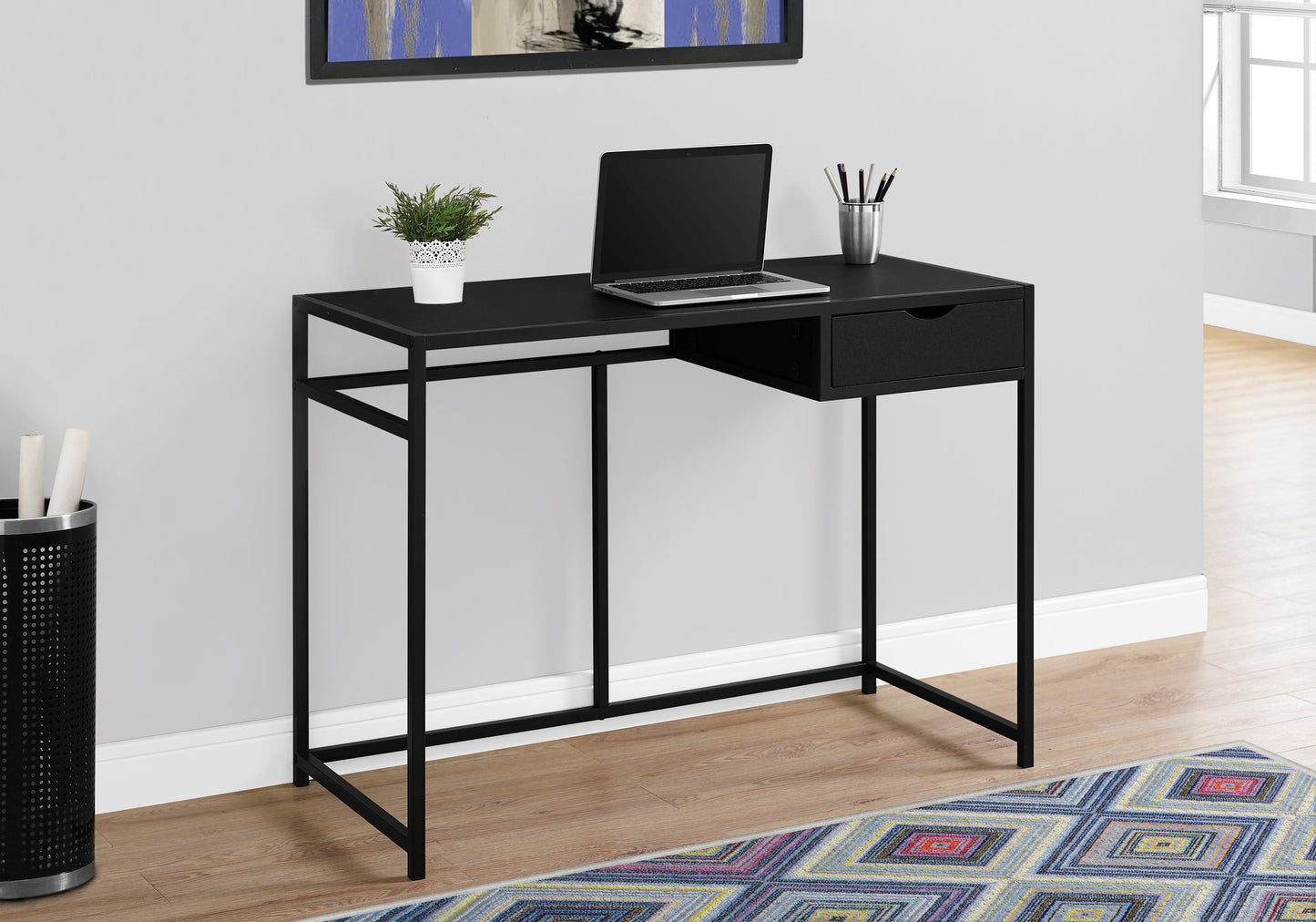 Sleek black metal frame writing desk with a single drawer and laptop