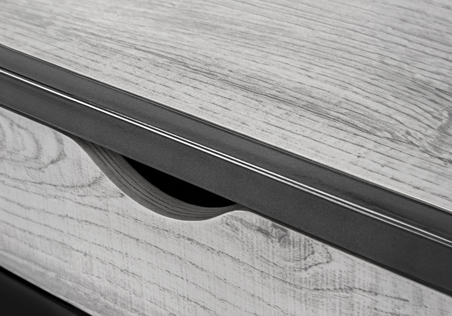 Close up of grey wood grain texture with a modern black metal drawer pull
