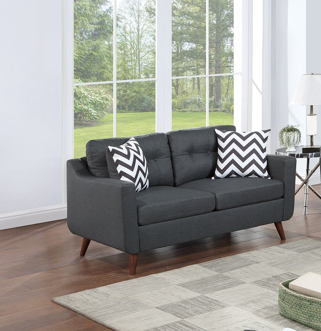 Dark gray tufted loveseat with midcentury modern tapered legs and chevron pillows