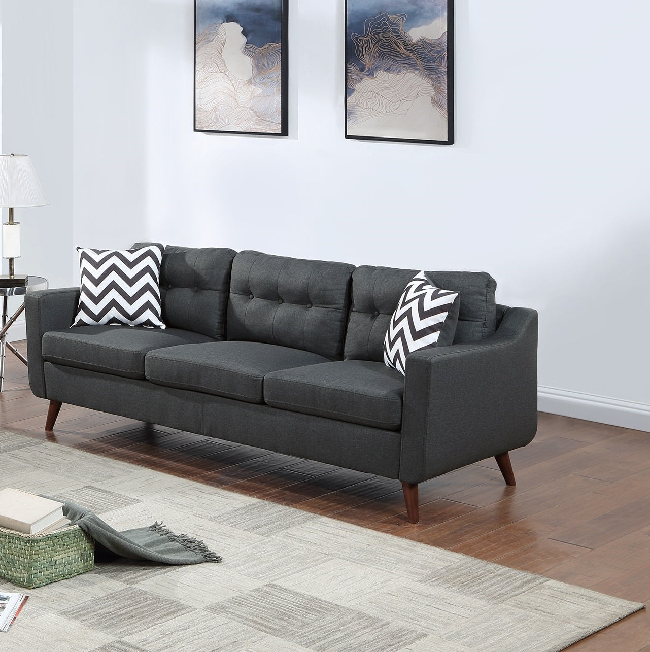 Dark gray tufted fabric sofa with tapered wooden legs and chevron pattern pillows