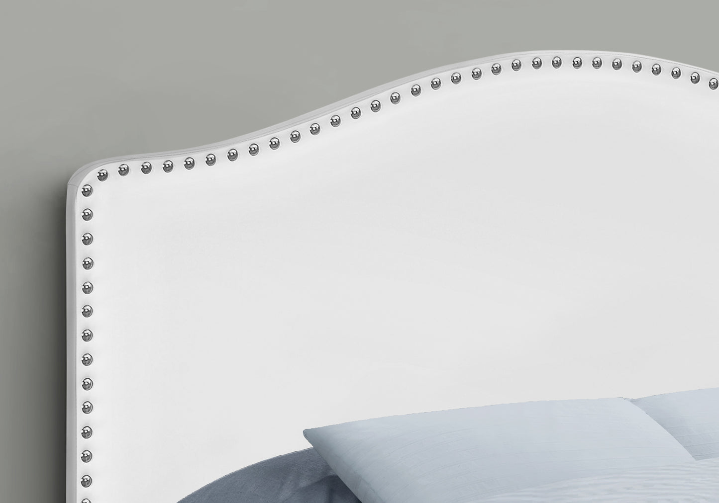White upholstered headboard with silver nailhead trim detailing