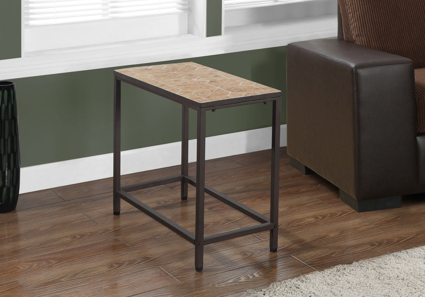 A slender metal end table with a geometric tiled top sits next to a brown leather sofa