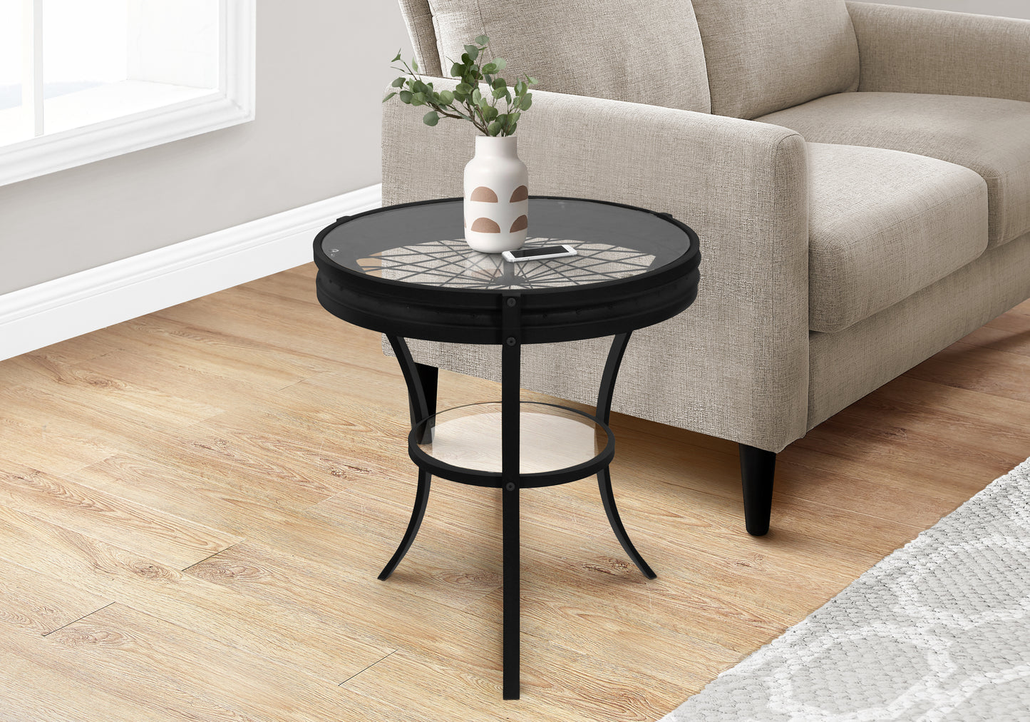 Black metal end table with round glass top featuring decorative inlay and lower shelf