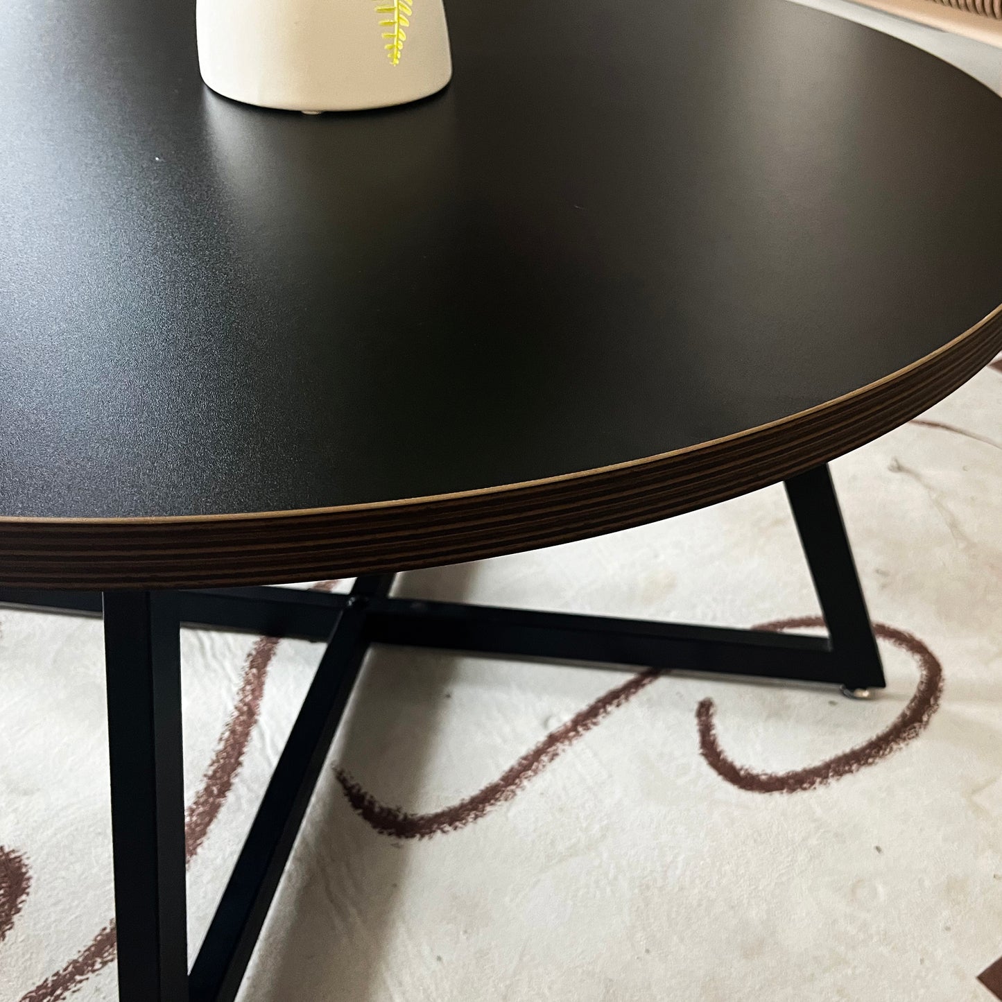 Black round coffee table with a modern geometric metal base perfect for living rooms