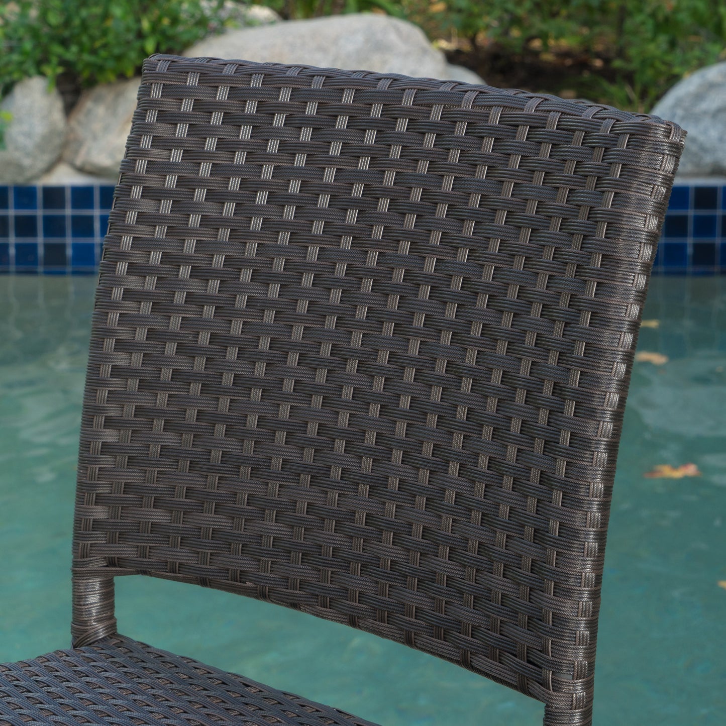 Dark brown wicker patio chair back with intricate weave pattern