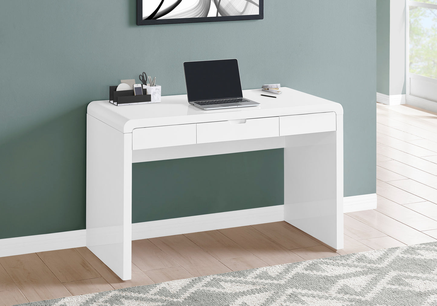 Modern white writing desk with rounded edges and three drawers laptop included
