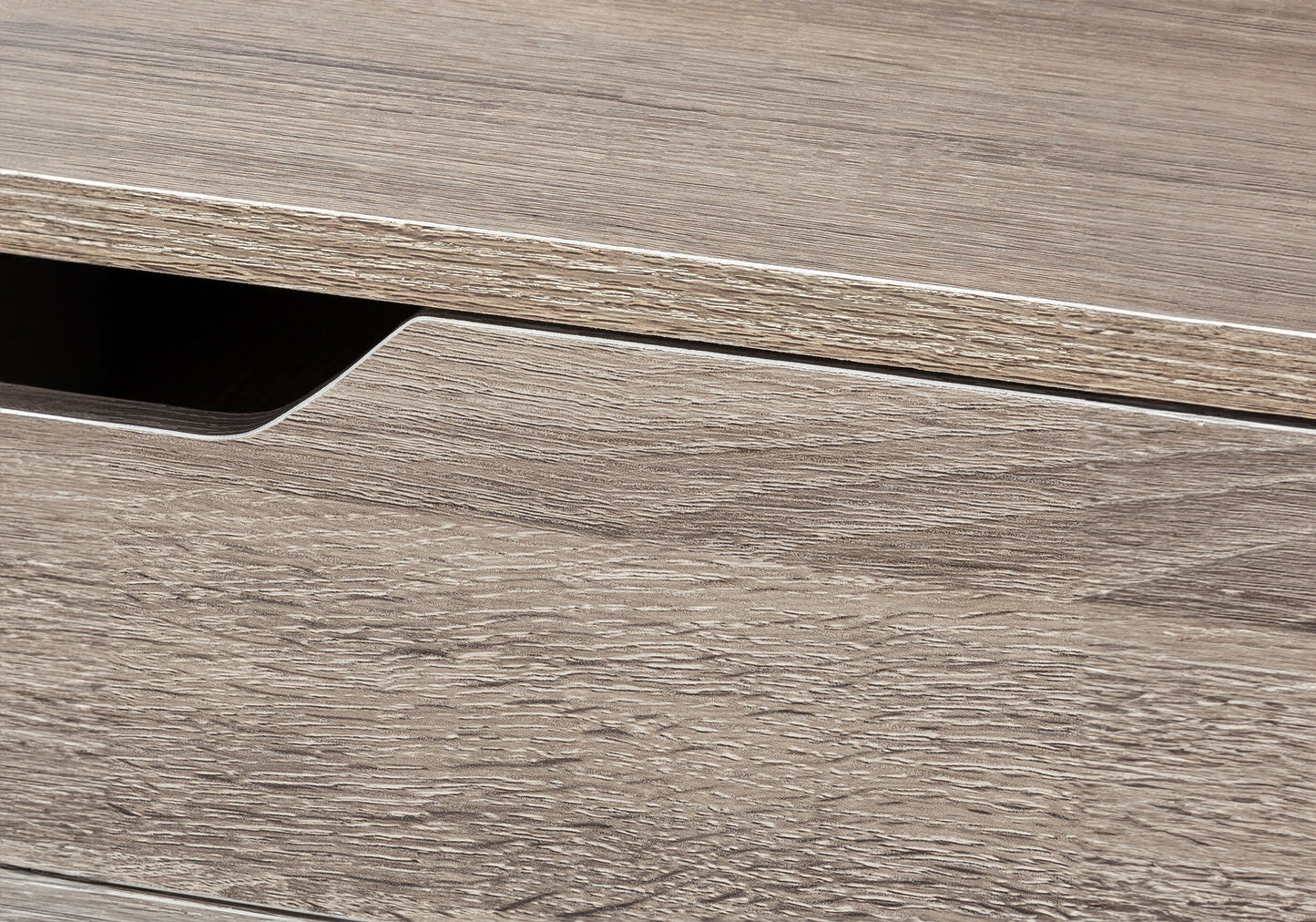 Closeup of a grey oak veneer drawer front with a silver trim and handle recess