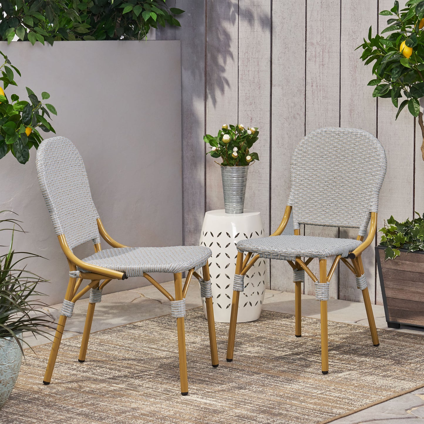 Pair of grey wicker bistro chairs with gold metal frames for outdoor dining