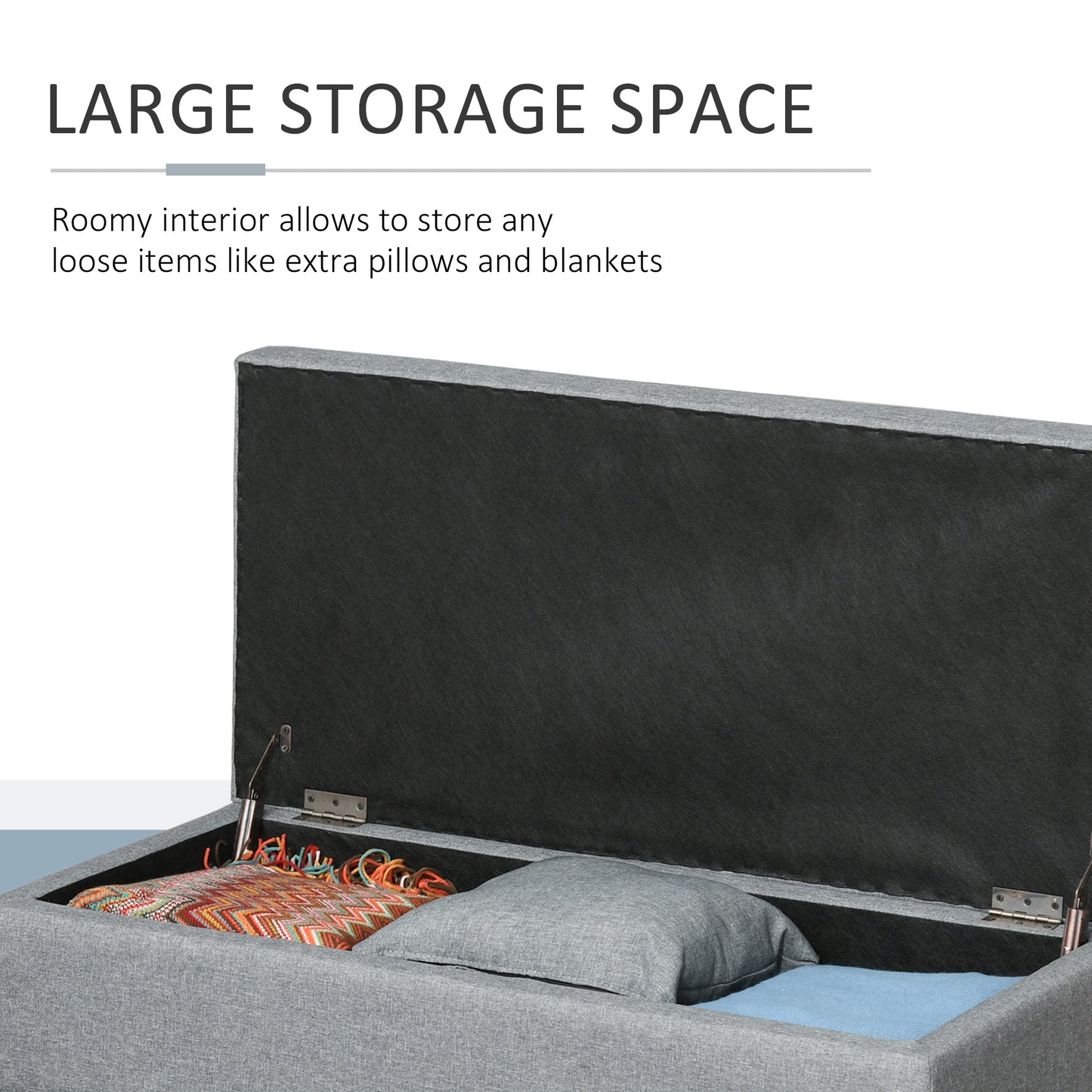 Gray fabric storage ottoman with lid open revealing blankets and pillow inside