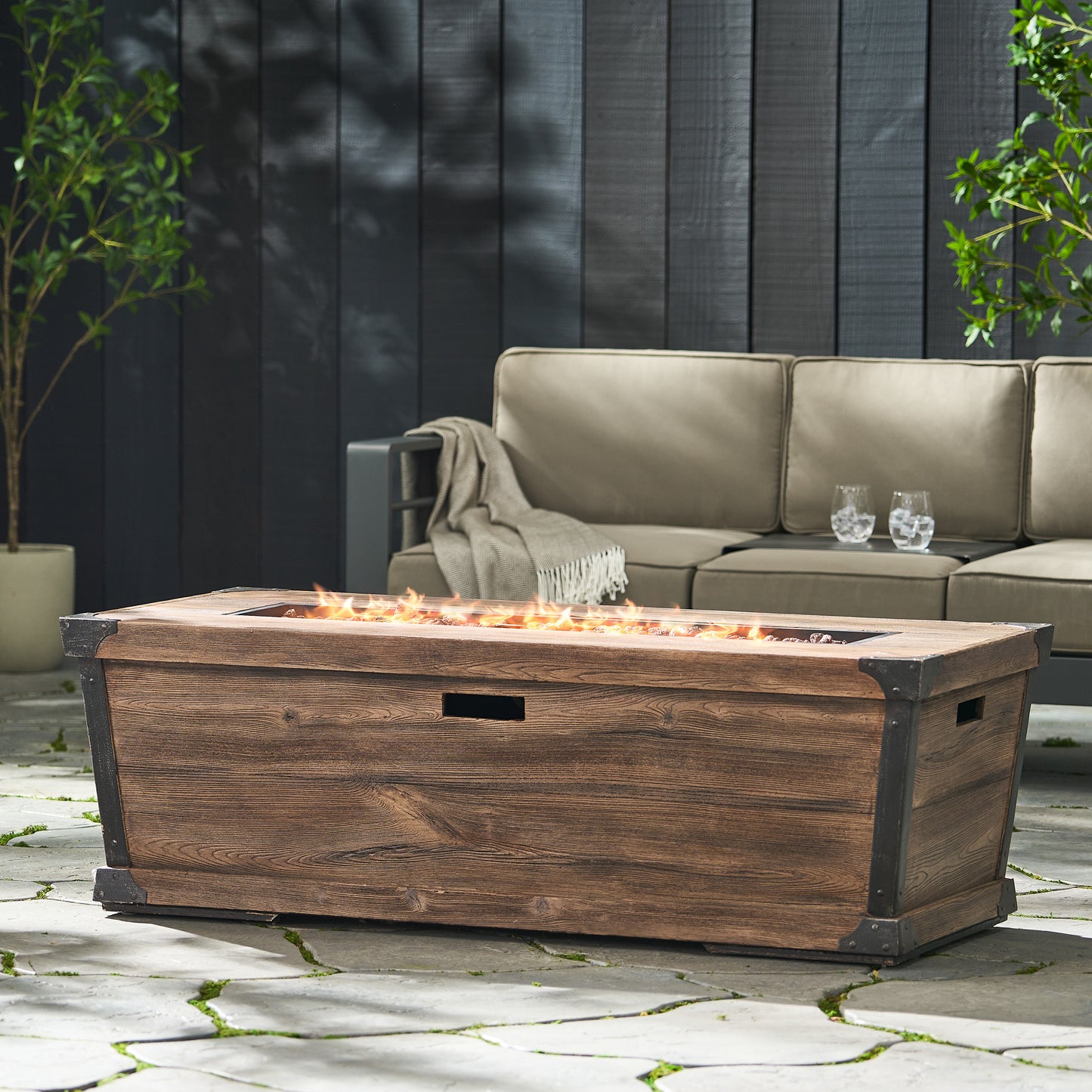 Rustic wooden outdoor propane fire pit table with black metal accents and roaring flames