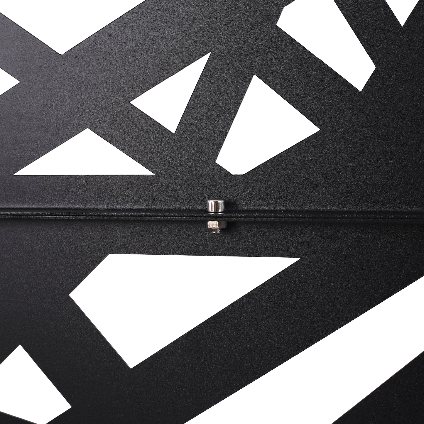 Closeup of a black metal decorative panel with abstract geometric cutouts and visible bolt