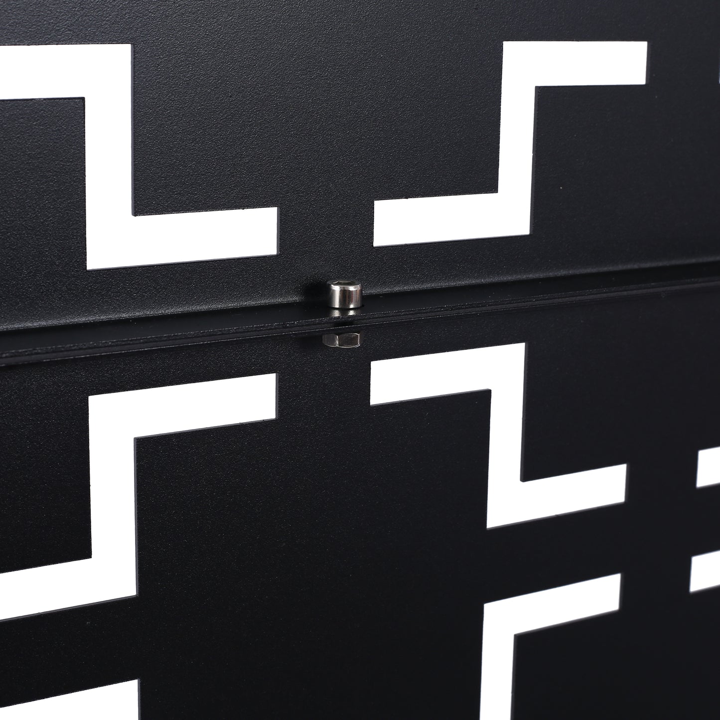 Closeup of black textured metal panel with white geometric cutouts featuring a metallic screw