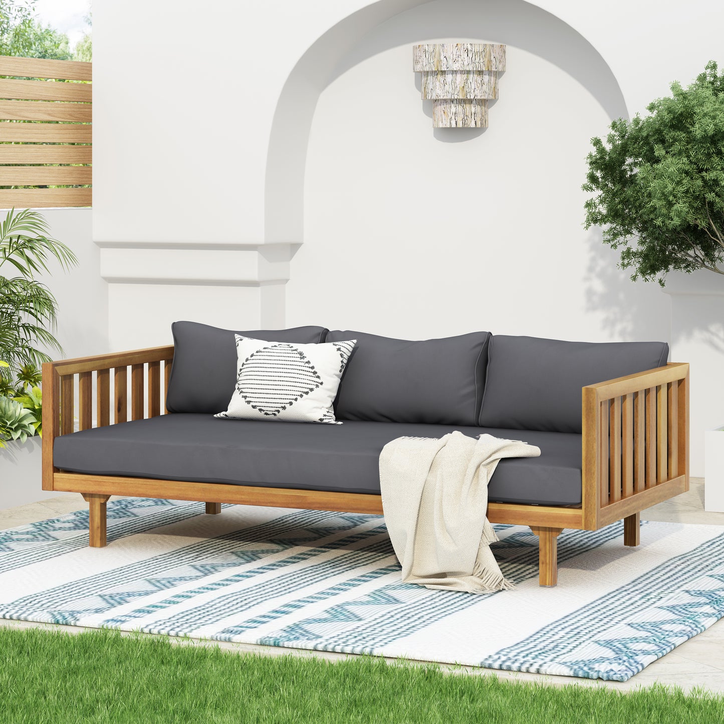 Wooden outdoor daybed with charcoal grey cushions and striped throw