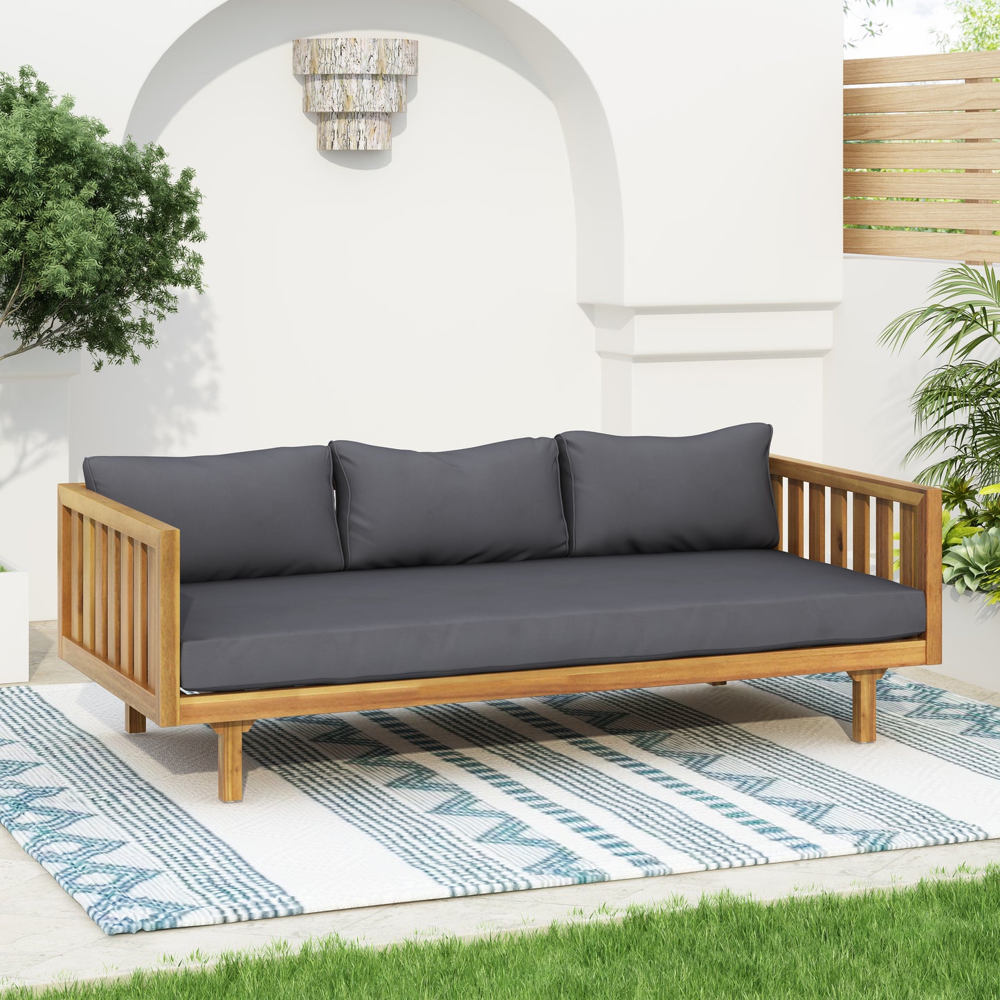 Acacia wood outdoor daybed with three charcoal gray cushions perfect for patio lounging