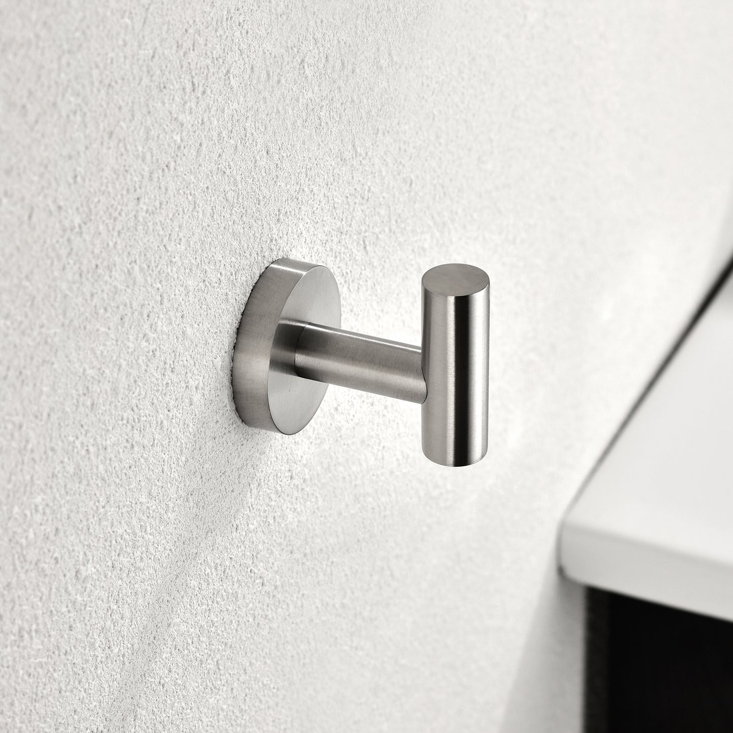 Brushed nickel towel hook with minimalist design on textured white wall
