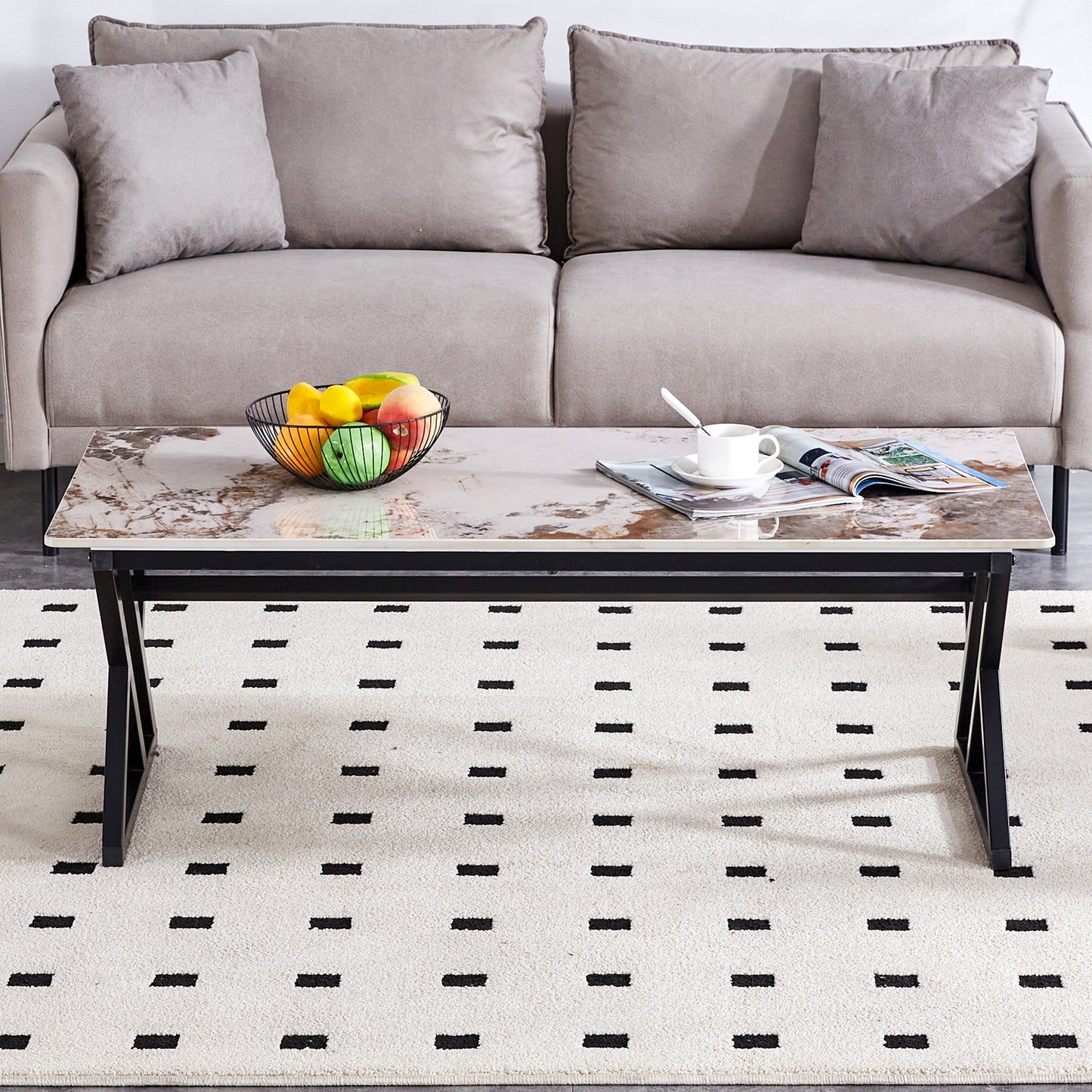 Rectangular marble effect coffee table with black metal legs and a fruit bowl