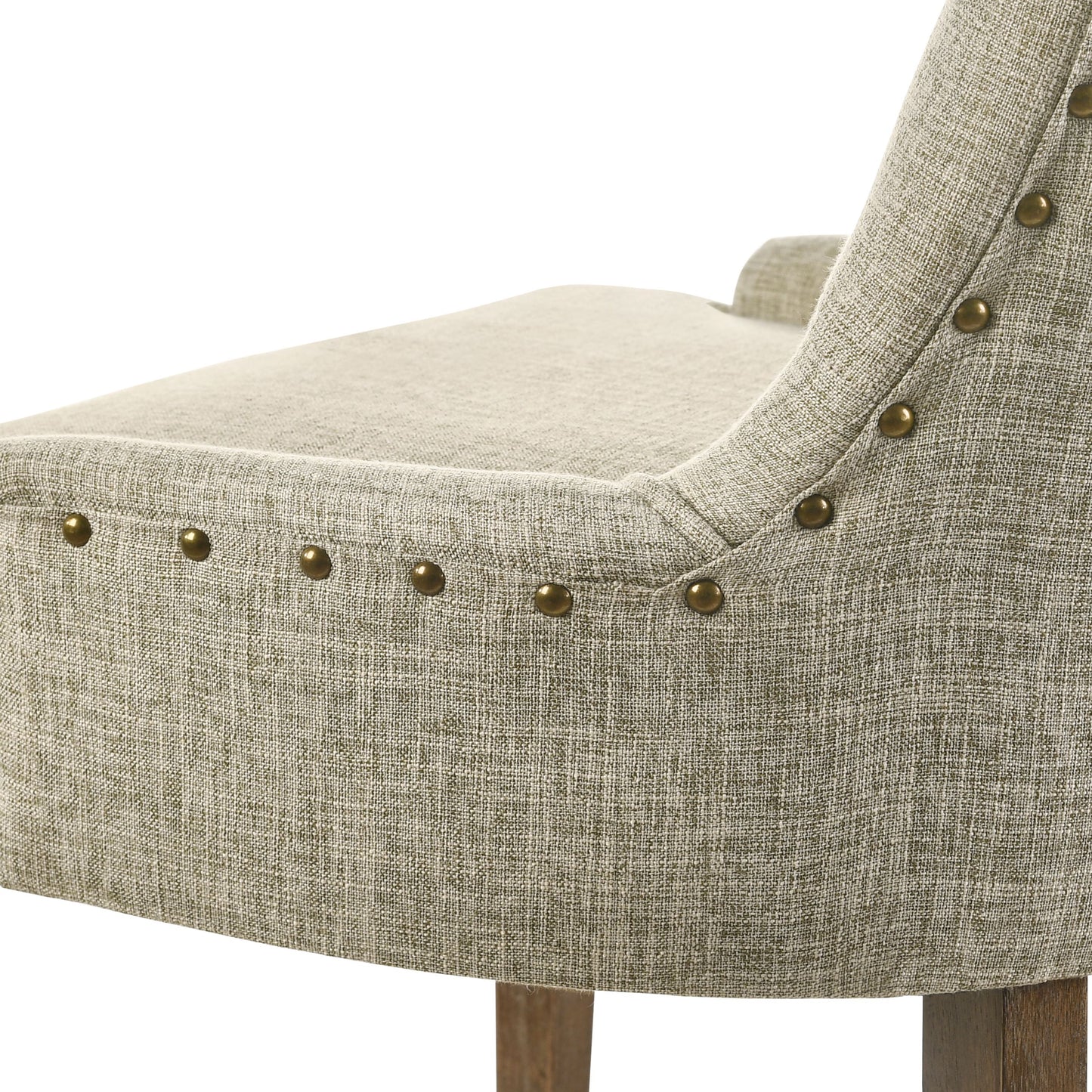 Closeup of a beige linen upholstered dining chair with brass nailhead trim