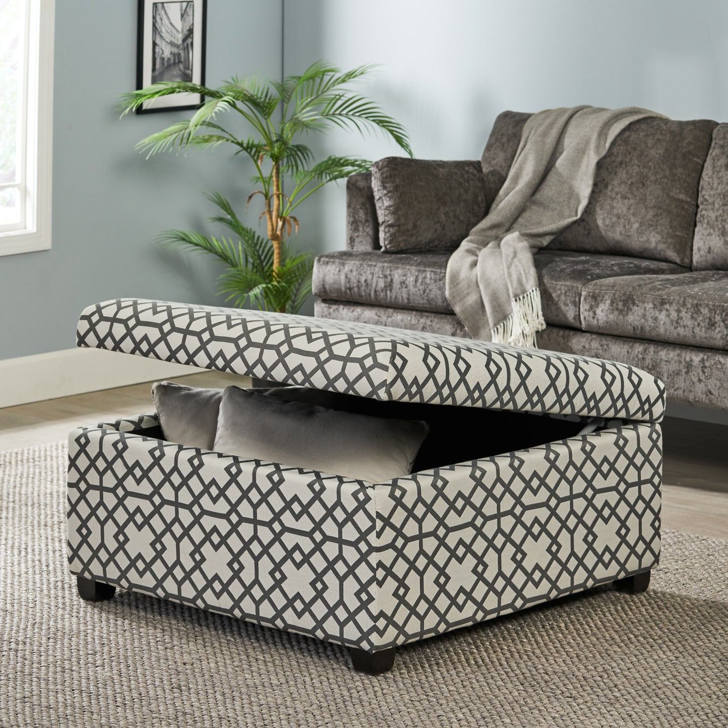 Geometric pattern storage ottoman with open lid revealing grey pillows