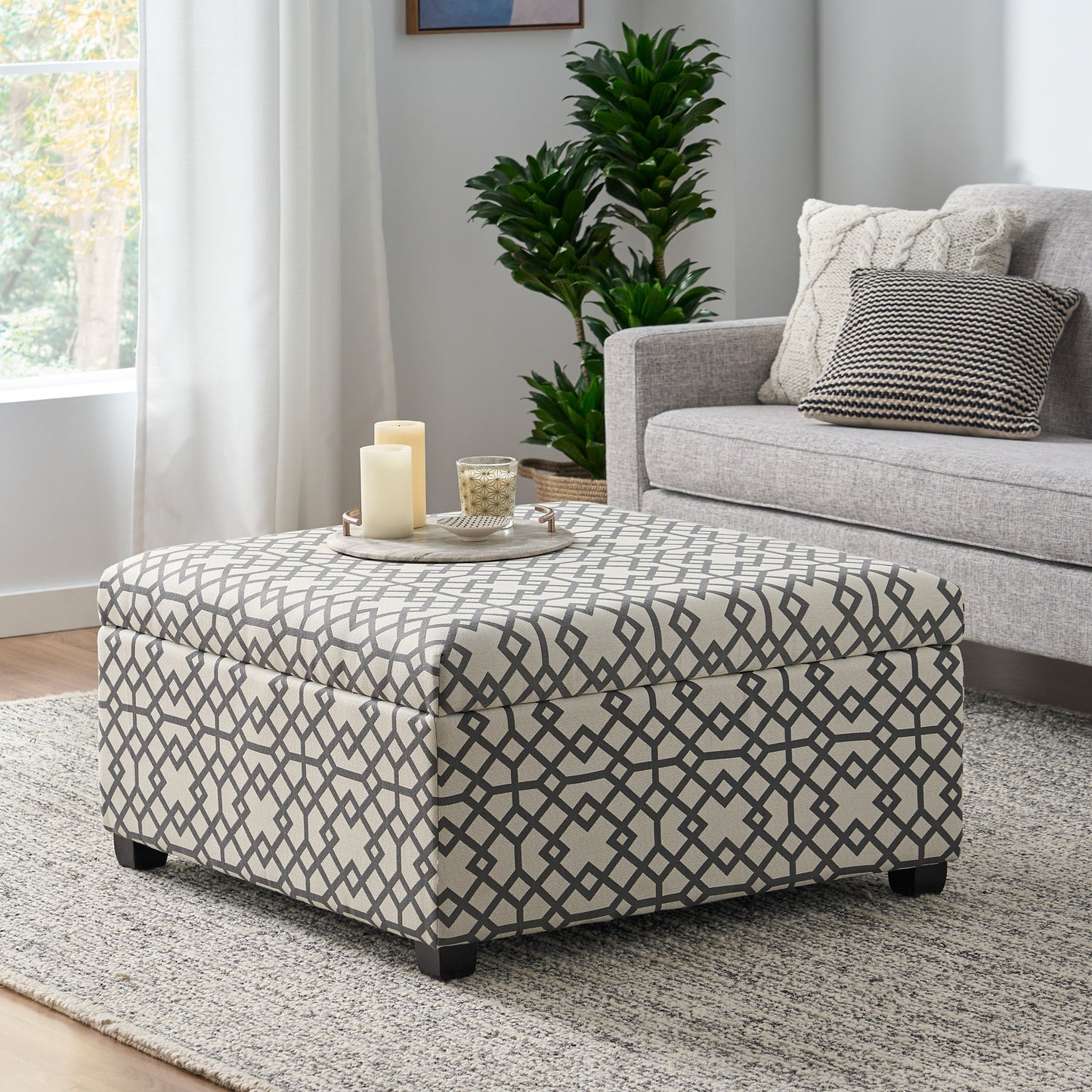 Storage ottoman with gray geometric pattern upholstery and dark wooden legs