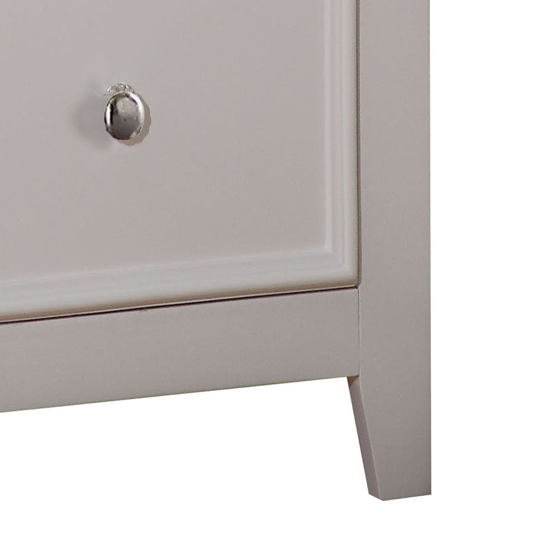 Closeup of a light gray dresser drawer with a silver knob and paneled detail