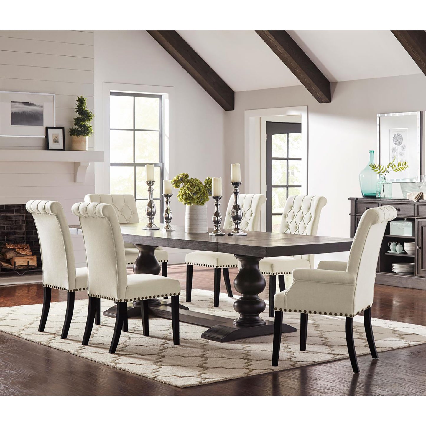 Tufted cream dining chairs with nailhead trim complement a dark wood pedestal dining table