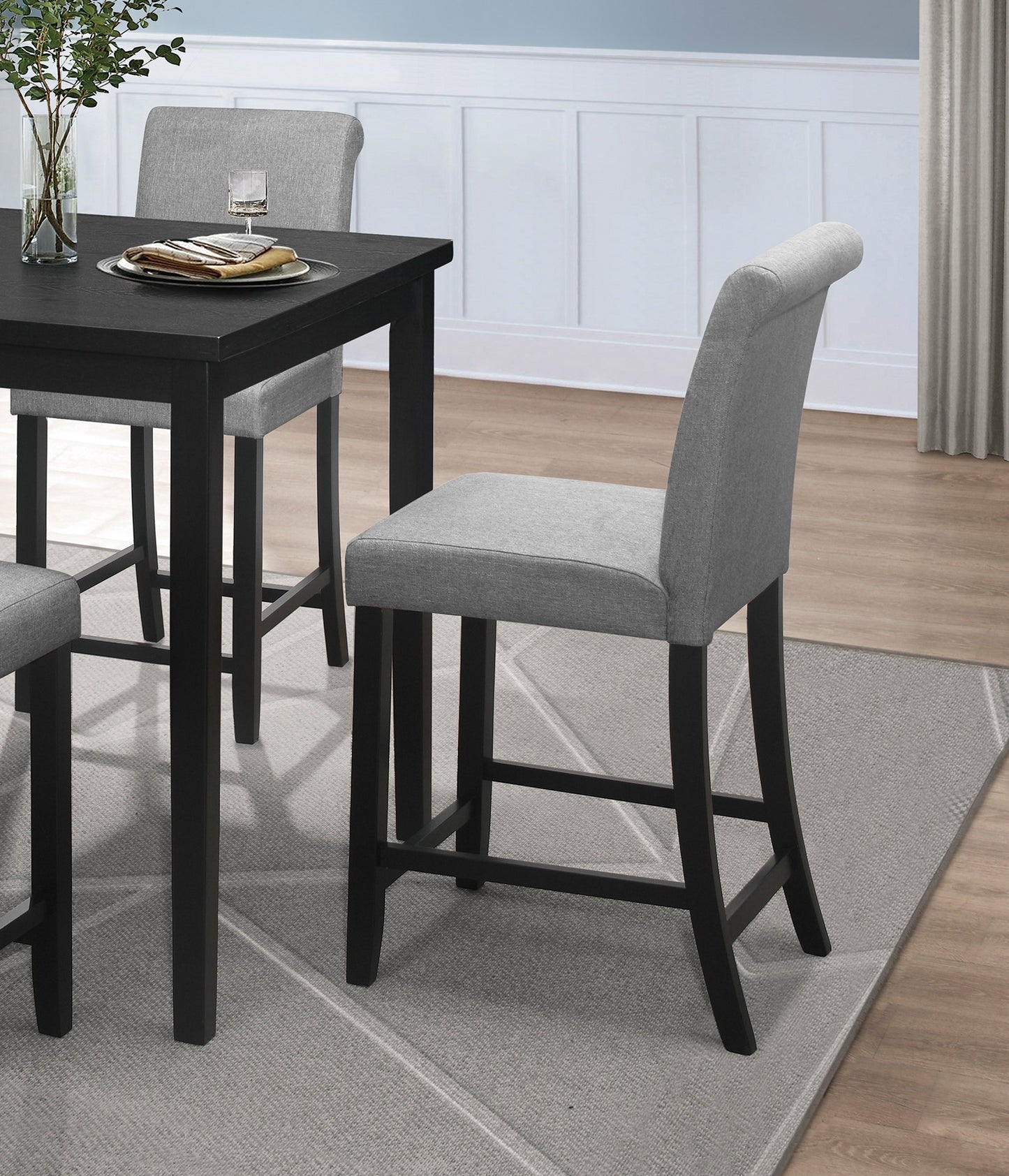 Grey upholstered bar stool with black wooden legs part of a dining set