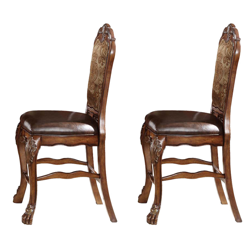 Two ornate dark brown upholstered dining chairs with carved wooden legs and patterned backs