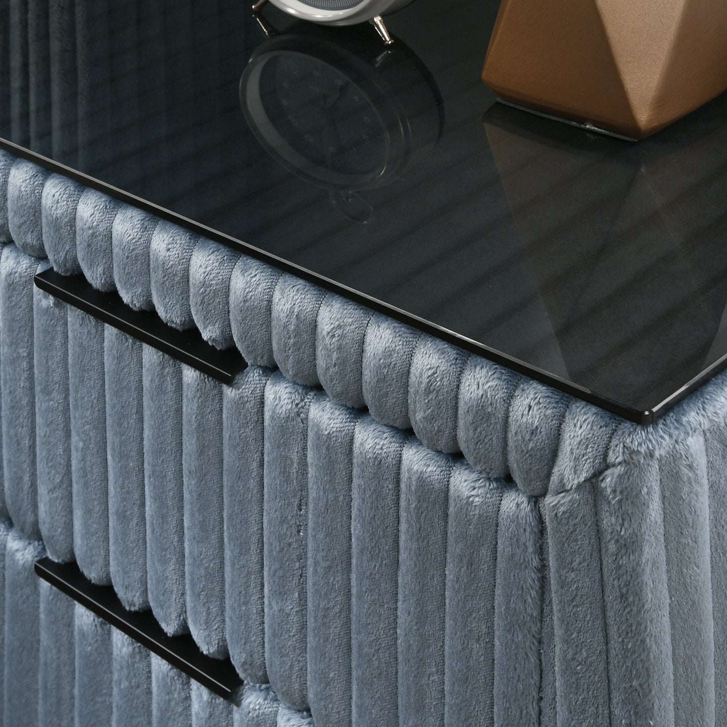 Plush blue velvet dresser with sleek black handles and a dark glass top