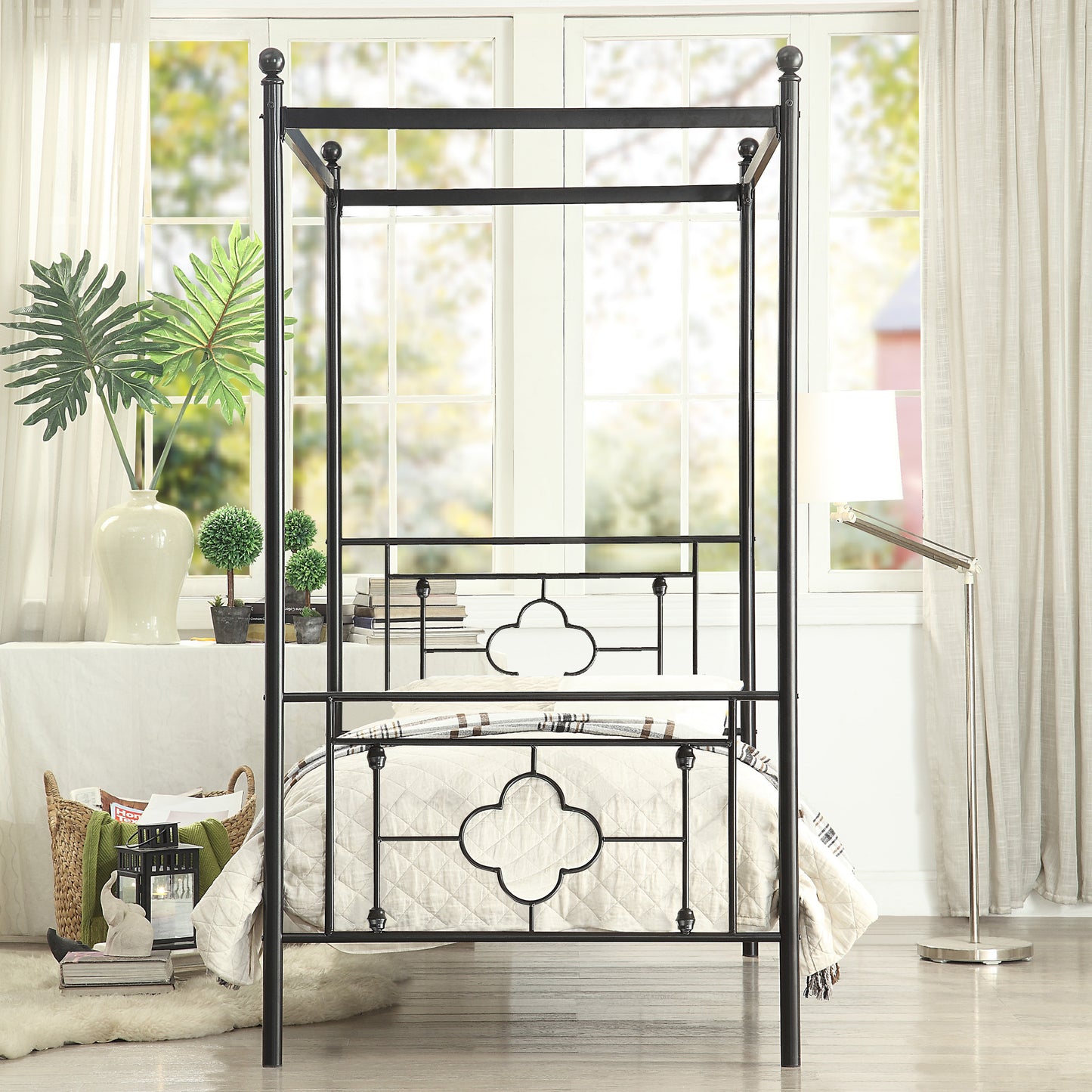Black metal canopy bed frame with quilted bedding and decorative scrollwork headboard