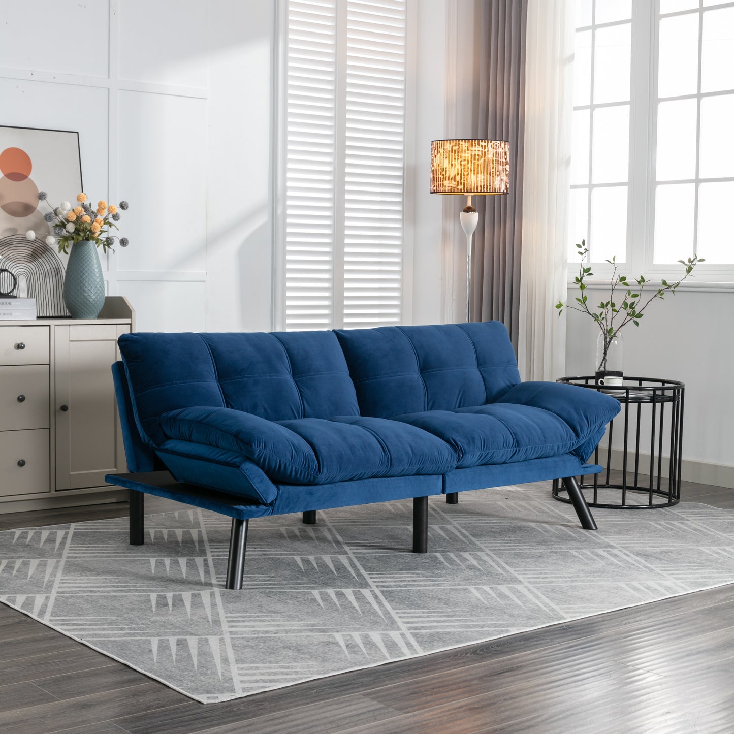 Plush navy blue velvet sofa bed with tufted cushions and black metal legs