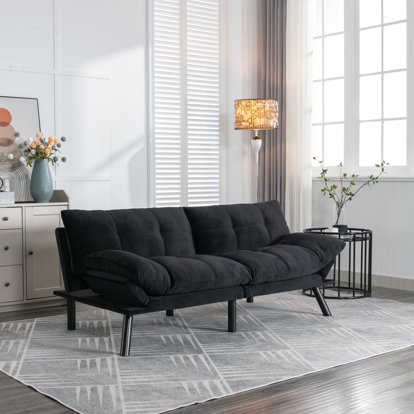 Black velvet futon sofa with tufted cushions and metal legs ideal for small apartments