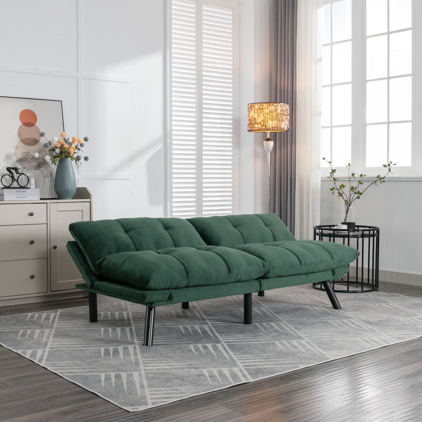 Modern dark green futon sofa with tufted cushioning and chrome legs in a living room setting