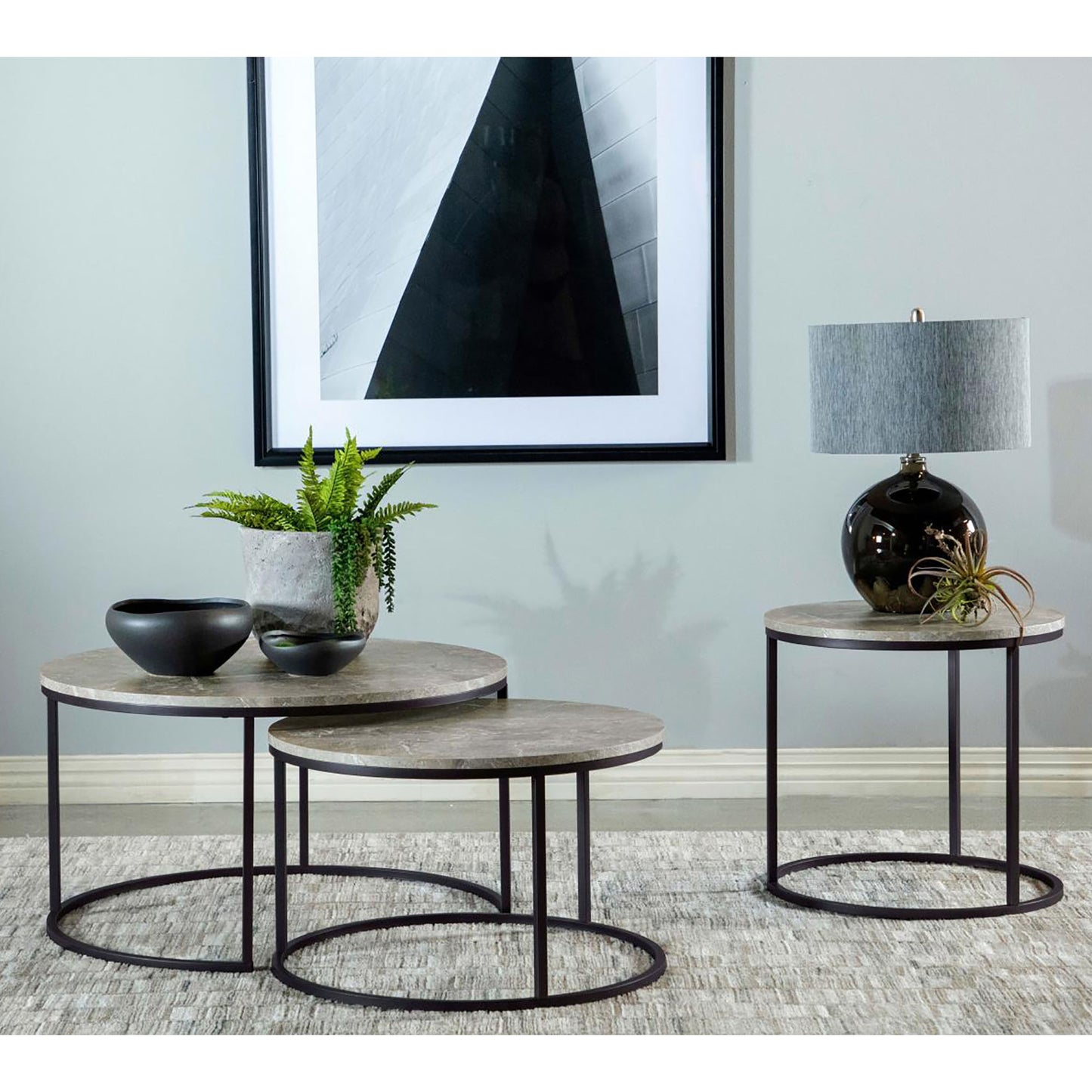 Marble nesting coffee tables with black metal legs and abstract art