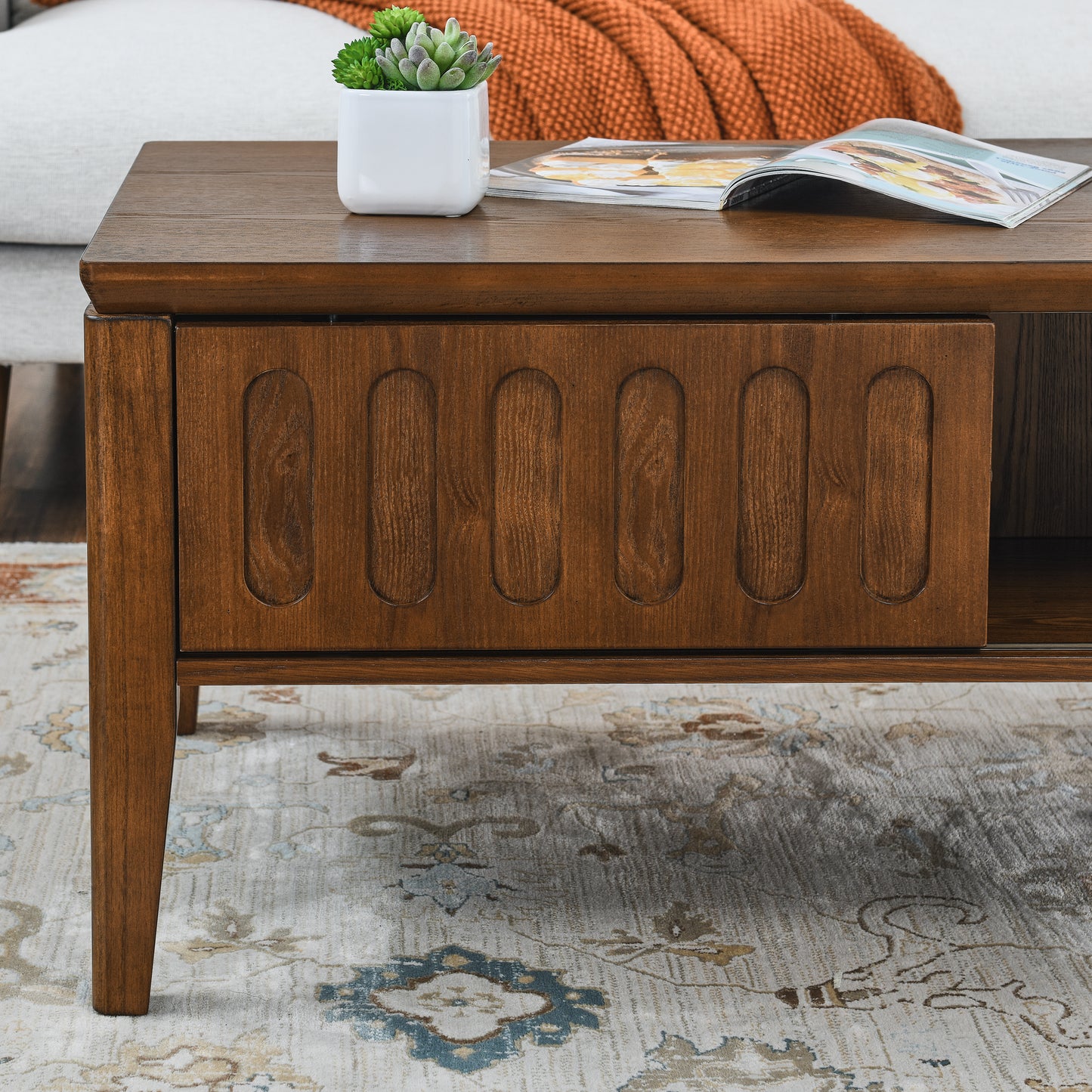 Rich brown wood coffee table with carved oval accents on drawer front