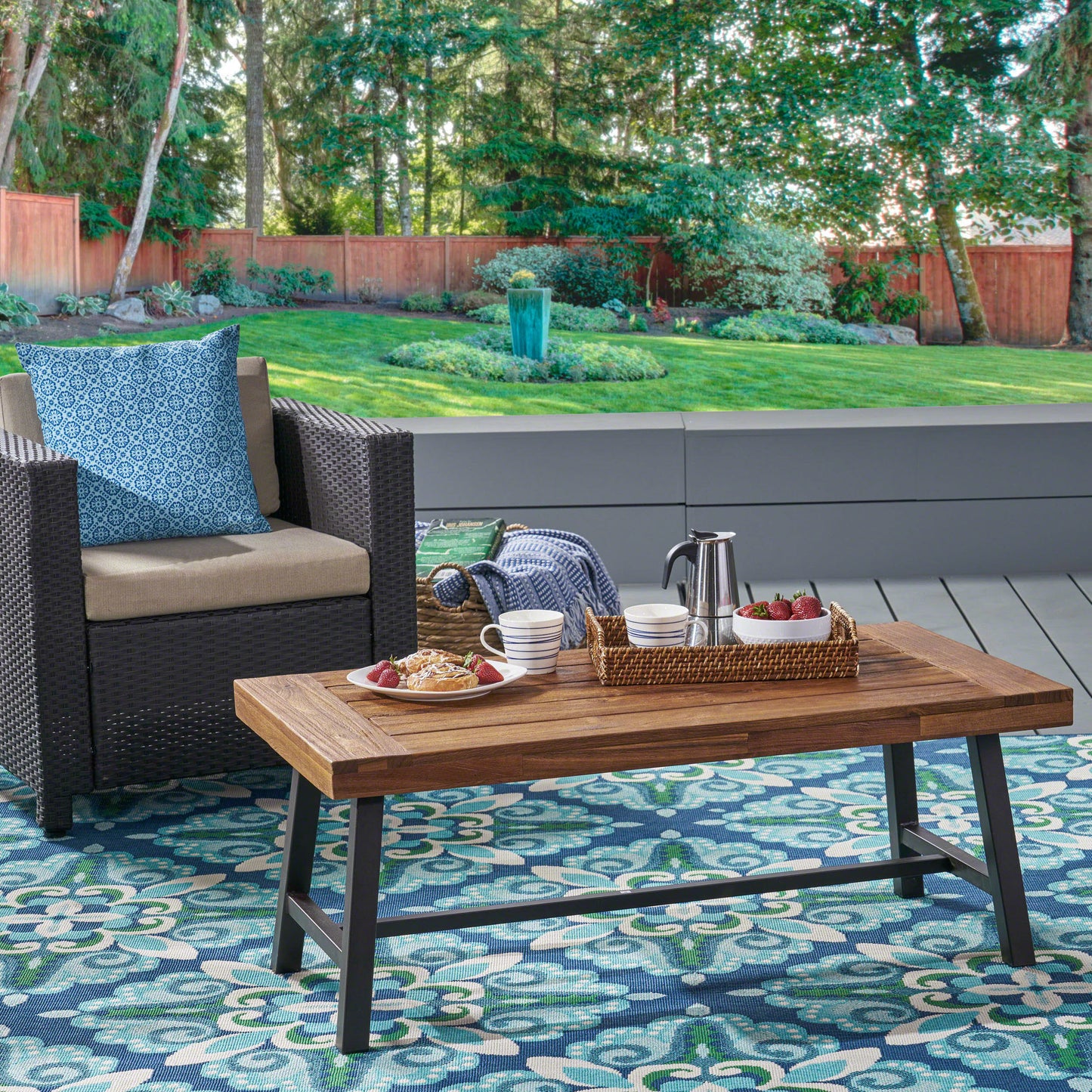 Woven rattan armchair with beige cushion and blue patterned outdoor pillow